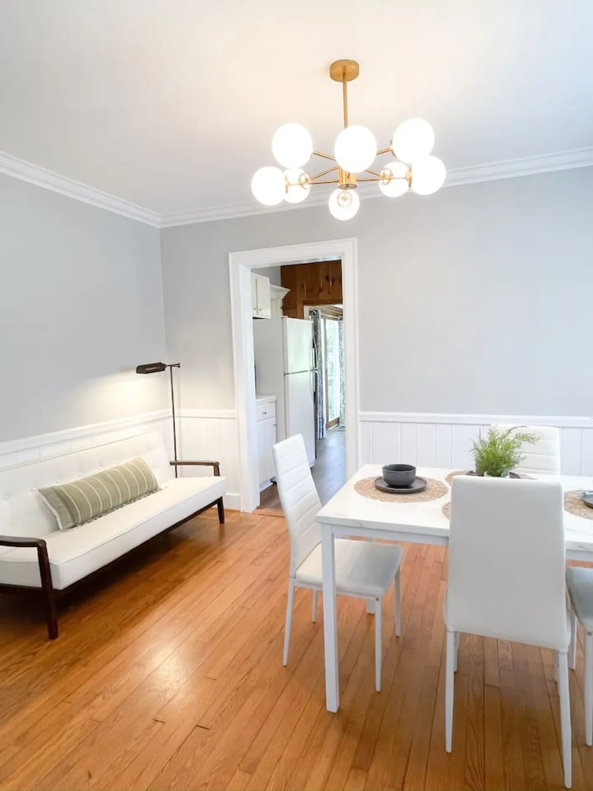 A warmly lit dining area featuring a dining table under a chandelier, adjacent to a comfortable sofa. The setting feels intimate and welcoming, perfect for shared meals, celebratory brunches, or lingering over morning coffee before venturing out.